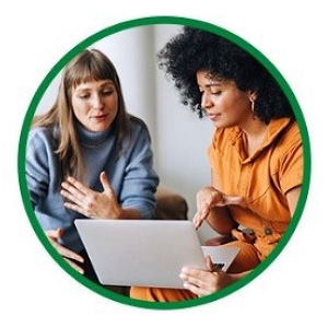 Two Female Work Colleagues Engaged in Conversation while Reviewing a Laptop Screen